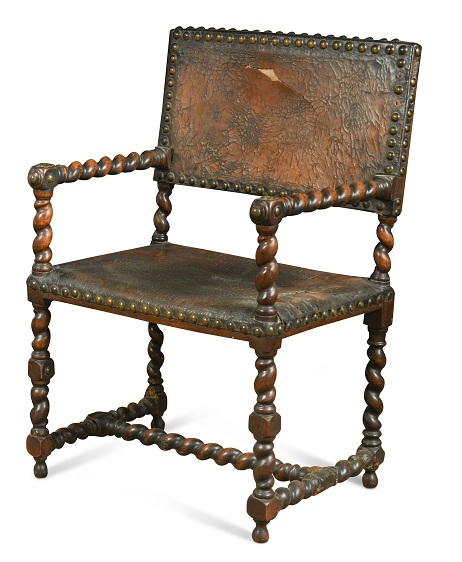 A late 17th century walnut framed armchair, the twist carved frame with leather brass nailed back