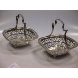 A pair of George V silver fruit baskets, with pierced sides and fixed scroll handles, raised on