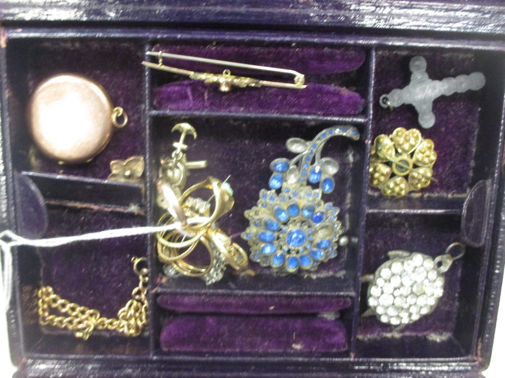 A red leather jewellery case containing a collection of gold jewellery and a gold watch together