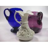 An amethyst glass jug, a Beleek style ewer, Bristol blue jug and other glassware