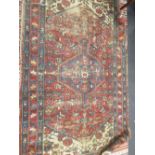 A red ground rug with central lozenge and carnation motifs (worn) 197 x 131cm
