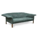 A large modern blue/green suede effect three-seat sofa, the back and arms with exaggerated overhang,