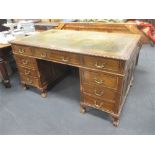 An early 20th century mahogany pedestal desk with carved rim and raised on short legs with ball