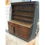 An 18th century oak dresser with drawers and cupboards below and associated plate shelves above