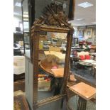 A large gilt framed wall mirror, with trophy cresting, 132 x 52cm