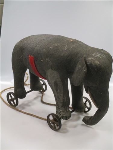 A large Steiff elephant on wheels, grey felt with white felt tusks, remnants of the red and gold