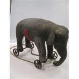 A large Steiff elephant on wheels, grey felt with white felt tusks, remnants of the red and gold