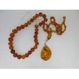 A Russian amber pendant on necklace together with a loose string of vintage amber beads,