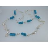 A long necklace of cultured freshwater pearls and carved turquoise-coloured beads,