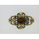 A Victorian citrine brooch in an ornate mount,