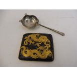 A silver strainer/sifting spoon and an Oriental lacquered cigarette case.