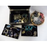 A jewellery box containing an assortment of costume jewellery and a small basket of necklaces etc.