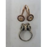 A pair of unusual silver earrings and a white metal ring in the form of a ram's head.