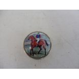 A circular silver and enamel topped pill pot, the lid decorated with a jockey cantering on his