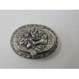 A Continental silver oval lidded box, the lid with a scene of musicians in deep relief.