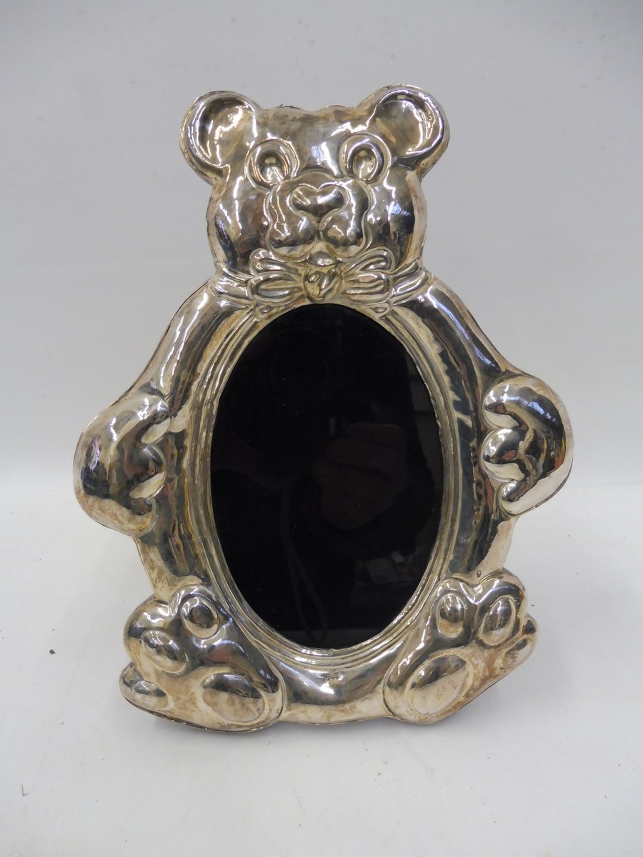 A contemporary silver fronted easel photograph frame in the shape of a teddy bear