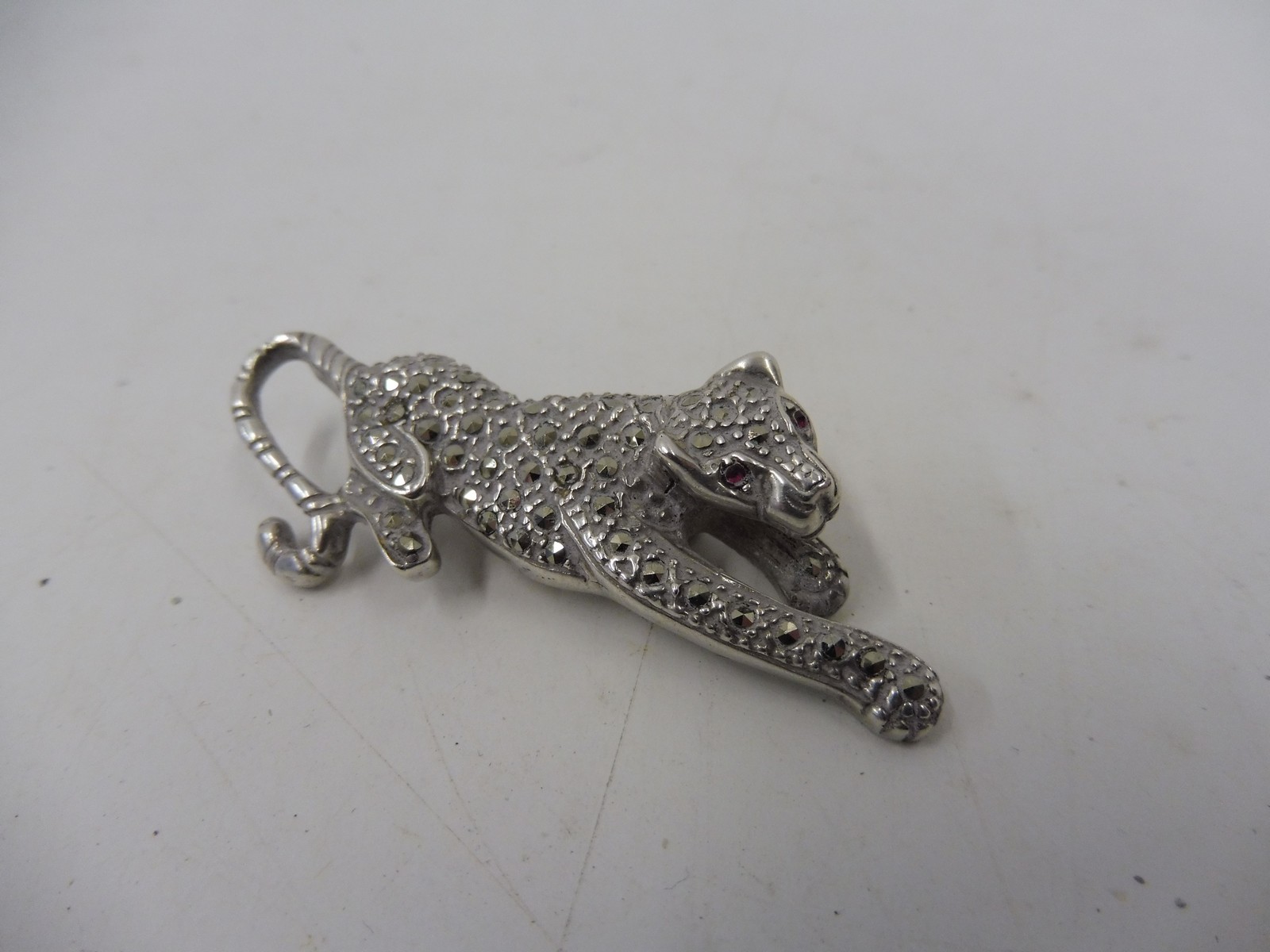 An unusual cased silver brooch in the form of a recumbant wild cat, all over encrusted with