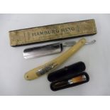 A cased silver mounted cheroot holder and a cut throat razor engraved 'The Hamburg Ring'.