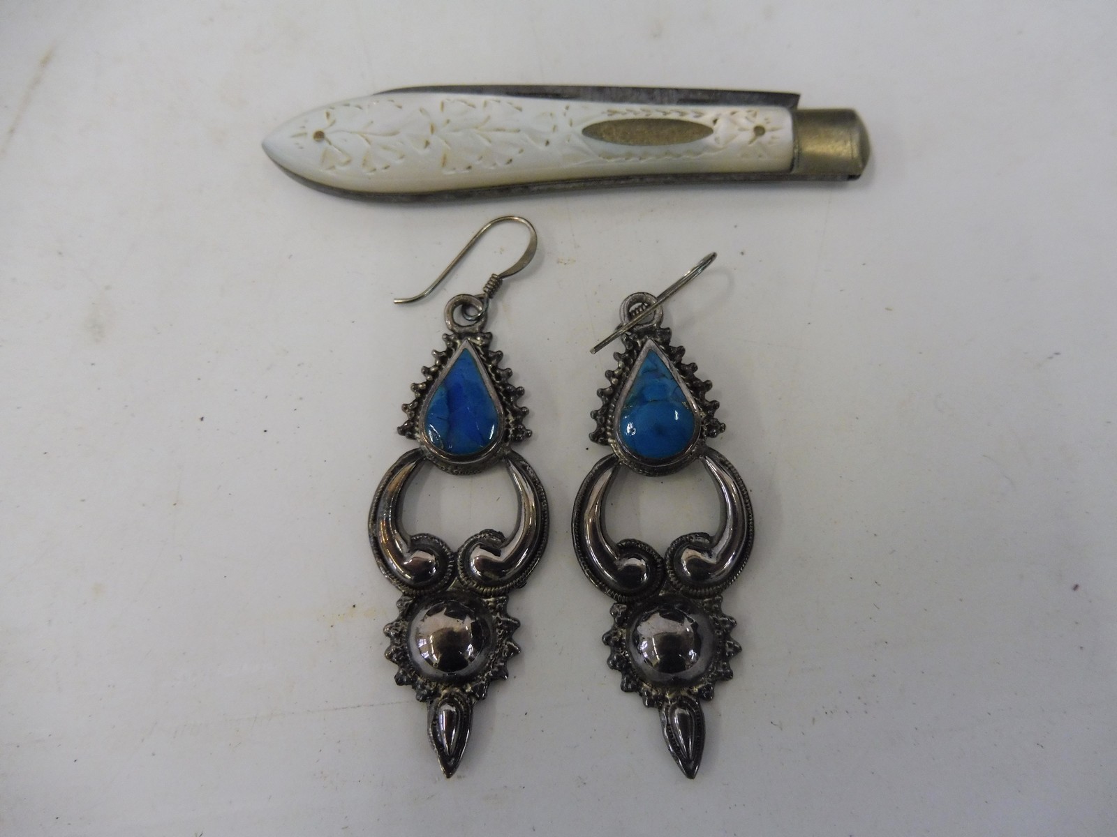 A pair of unusual silver earings set with turquoise coloured stones, and a silver and MOP handled