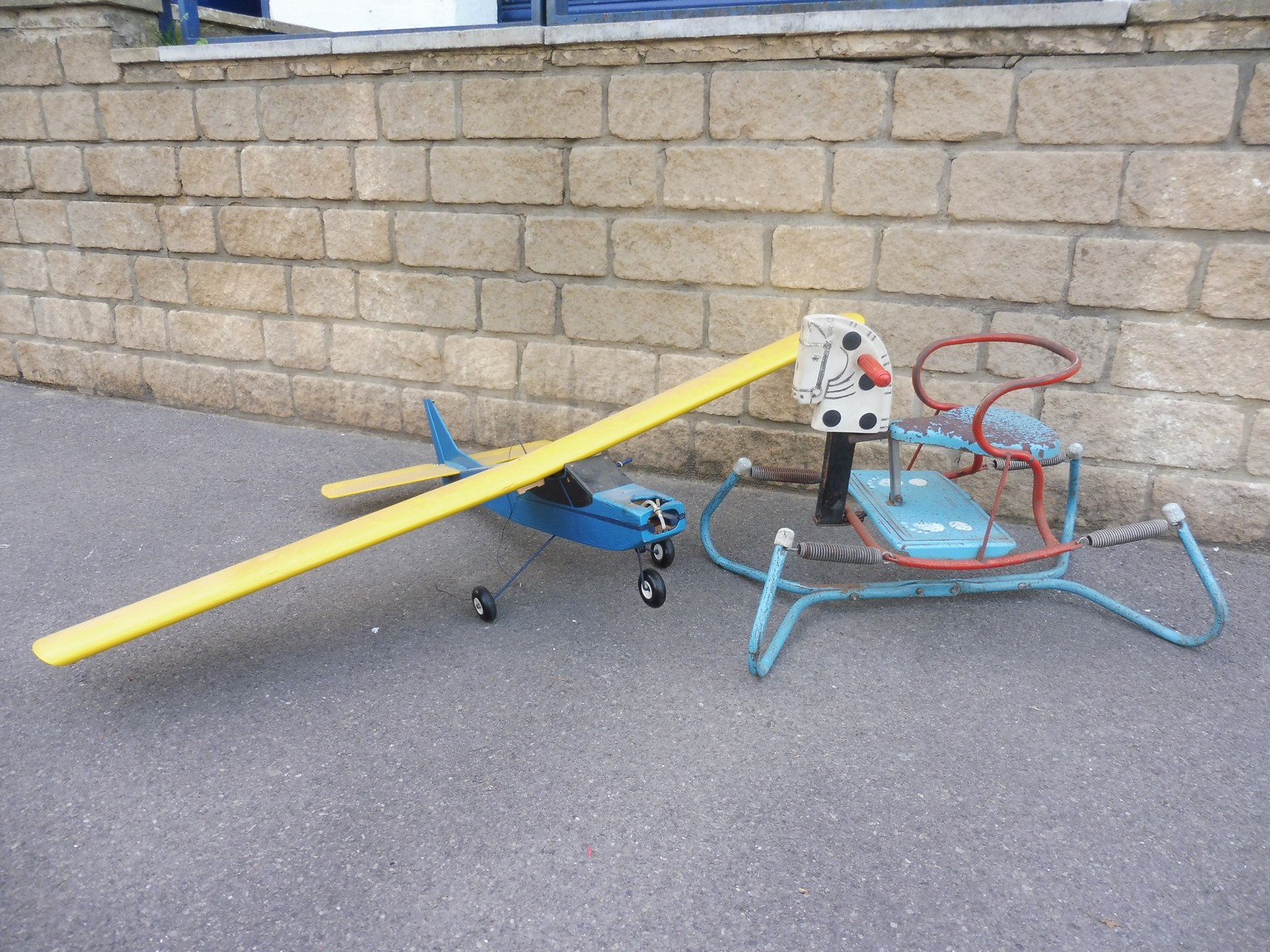 A tinplate child's rocker and a partial remote controlled model airoplane.