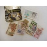 A tin of mixed Continental coins and bank notes, plus a Bank of England early issue £5 note in a