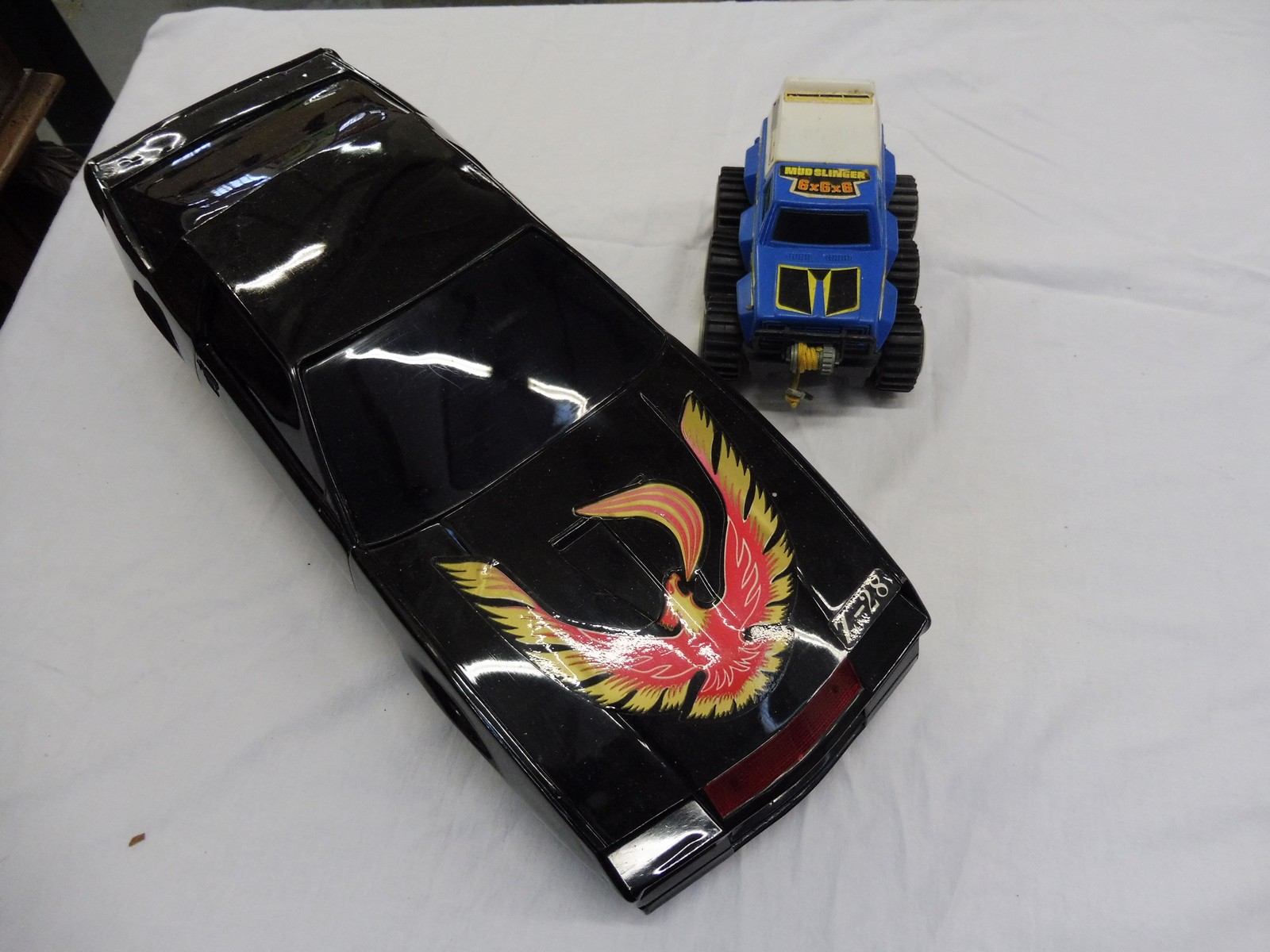 An original 1980s Nikko Camero Z28 Firebird Bump and Go and a six wheel drive off-road truck, both