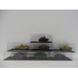 Seven cased scale model tanks.