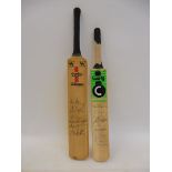 Two miniature cricket bats, each covered in autographs.