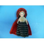 A late 19th century continental bisque head and shoulders Doll, dressed in skirts and red cloak, 7in