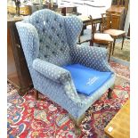 A George III-style wing Chair, the button-upholstered back with lugged sides and scrolled arms,
