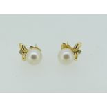 A pair of cultured pearl Earrings, set beneath with two leaves and a small diamond, mounted in