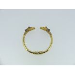 A hinged gold Bangle, with race horse head finials, the bangle with metal core and applied at the