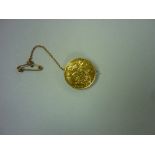 A George V gold Half Sovereign, dated 1915, mounted as a pin brooch with safety chain, together with