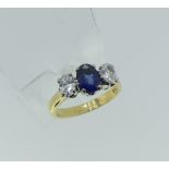 An attractive Sapphire and Diamond three stone Ring, the central oval facetted sapphire with an oval