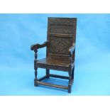 An 17th century carved oak Wainscot Armchair, the carved panelled back above a board seat and scroll