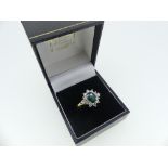 An emerald and diamond Dress Ring, the oval facetted emerald surrounded by ten circular diamonds and