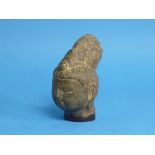 An antique Chinese carved stone head of Buddha, with downcast eyes in meditation, flanked by a large