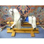 A Painted Wood Rocking Horse on Swingers, with white tail and mane, brown leather seat and reigns,