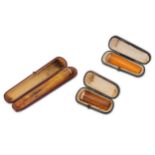 Three cased amber coloured cheroot holders, one with a 9ct gold mount