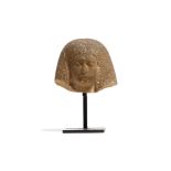 AN EGYPTIAN FEMALE LIMESTONE HEAD Possibly New Kingdom, Wearing a bag wig, the female figure is