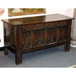 An oak coffer with twin panelled top and carved front,