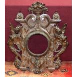 A carved oak frame with baskets of flowers finial and border of winged caryatids,