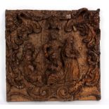 A carved oak panel with central figures within a scrolling surround, cherubs to the top corners,