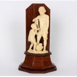 A French carved ivory figure of a child drinking water poured by a man,