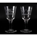 A pair of glass goblets engraved with cock fighting scenes to the tapering bowls, plain stems,