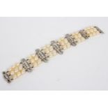 An Art Deco three-row cultured pearl bracelet joined by six diamond set spacers, 18.