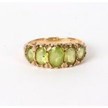 A peridot ring, the five oval graduated stones in a yellow gold scroll setting, approximately 4.