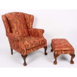 An upholstered wingback armchair, covered in stylised material,