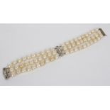 An Art Deco three-row cultured pearl bracelet joined by two diamond set spacers, 19.