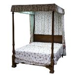 A Heals mahogany four poster bed with reeded posts and panelled headboard, hung floral curtains,